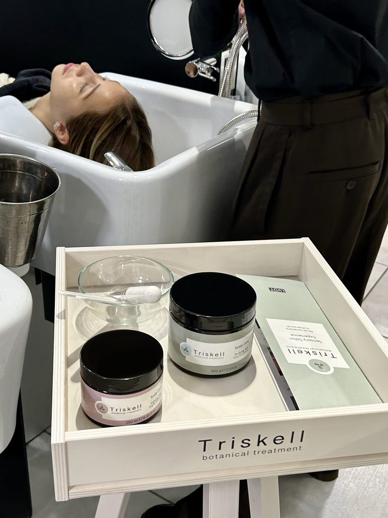 Cliente al lavatesta durante un trattamento, con il vassoio dei prodotti Triskell